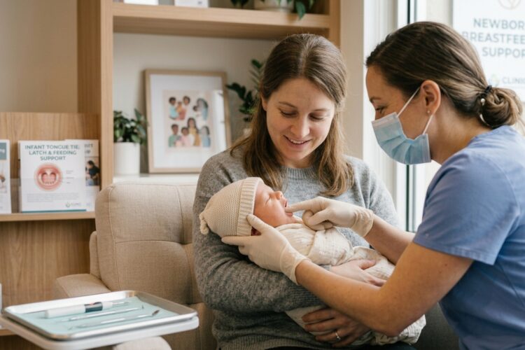 A pediatric dentist gently examining a newborn baby's mouth for infant tongue tie as the mother looks on at Family Dental Guelph.